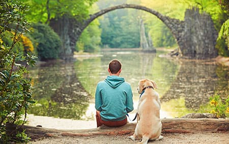 Junge mit Hund vor See mit Bogenbrücke